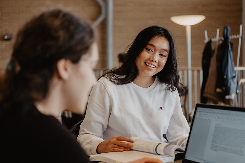 Två studenter samtalar i Lindellhallen på Umeå campus.