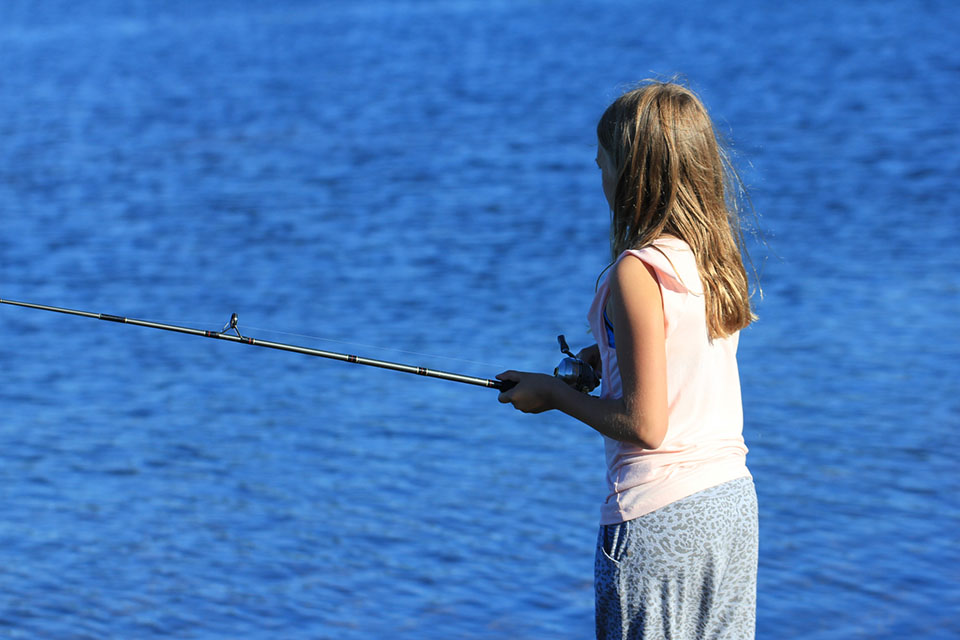 Flicka fiskar, blått vatten i bakgrunden