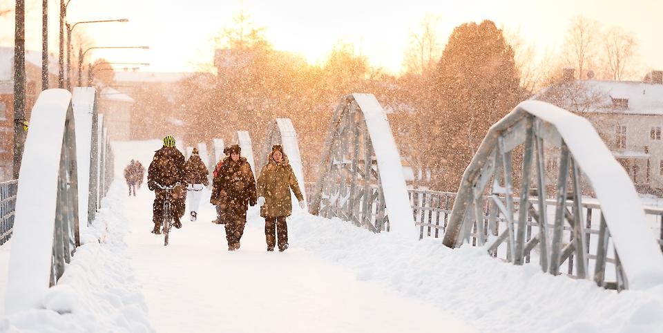 Människor promenerar över cykelbron i snöoväder