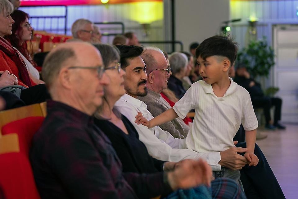 Barn som sitter i knät på en man i en aula
